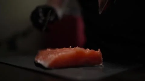 Close-Up of Hands Slicing Fresh Salmon Fillet on a Dark Background Vídeo Stock 303908199