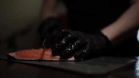 Close-Up of Hands Slicing Fresh Salmon Fillet on a Dark Background Stock Footage 303908209