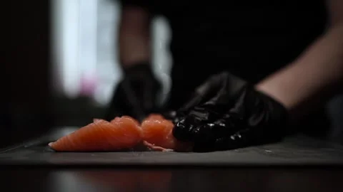Close-Up of Hands Slicing Fresh Salmon Fillet on a Dark Background Stock-Footage 303908235