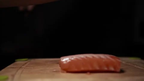 Close-Up of Hands Slicing Fresh Salmon Fillet on a Dark Background Stock Footage 303911615