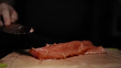 Close-Up of Hands Slicing Fresh Salmon Fillet on a Dark Background Видео 303911673
