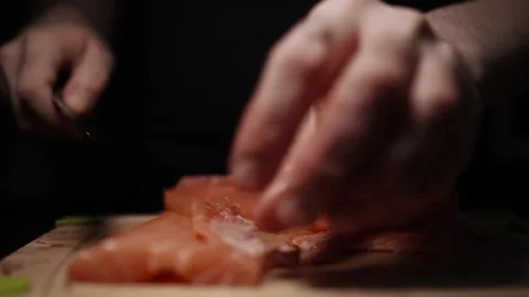 Close-Up of Hands Slicing Fresh Salmon Fillet on a Dark Background Video stock 303911686