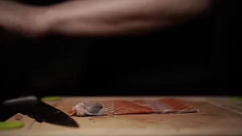 Close-Up of Hands Slicing Fresh Salmon Fillet on a Dark Background Video stock 303911702