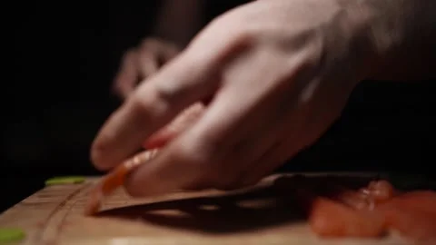 Close-Up of Hands Slicing Fresh Salmon Fillet on a Dark Background Stock Footage 303913883