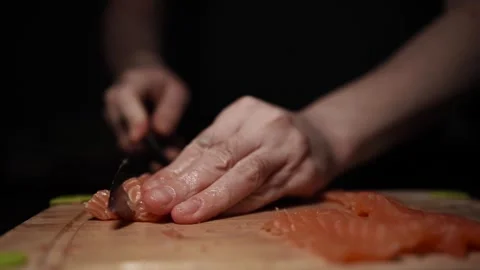 Close-Up of Hands Slicing Fresh Salmon Fillet on a Dark Background Stock Footage 303913889