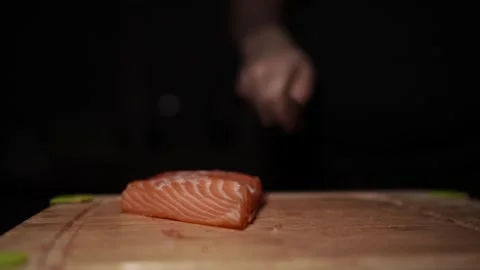 Close-Up of Hands Slicing Fresh Salmon Fillet on a Dark Background 스톡 동영상 303913894