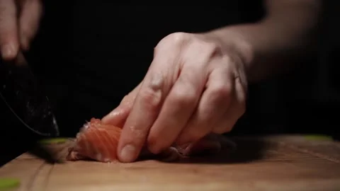 Close-Up of Hands Slicing Fresh Salmon Fillet on a Dark Background Video stock 303914084
