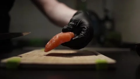 Close-Up of Hands Slicing Fresh Salmon Fillet on a Dark Background Видео 303914516