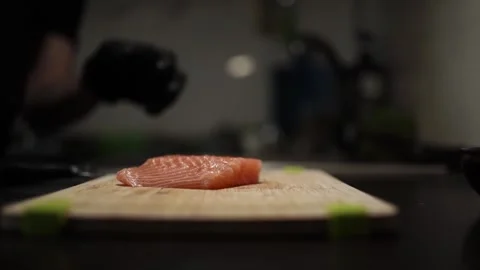 Close-Up of Hands Slicing Fresh Salmon Fillet on a Dark Background Video stock 303914591