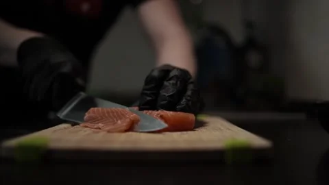 Close-Up of Hands Slicing Fresh Salmon Fillet on a Dark Background Video stock 303914593