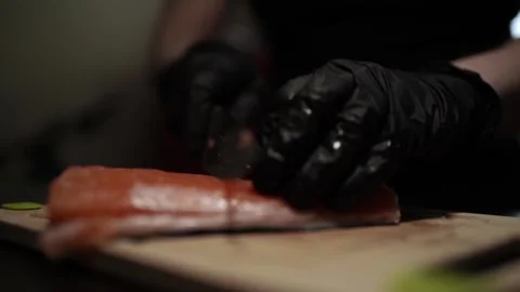 Close-Up of Hands Slicing Fresh Salmon Fillet on a Dark Background Video stock 303915069