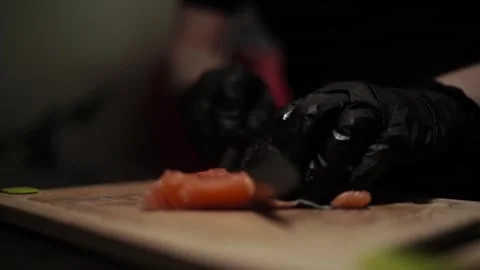 Close-Up of Hands Slicing Fresh Salmon Fillet on a Dark Background Stock Footage 303915734
