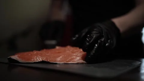 Close-Up of Hands Slicing Fresh Salmon Fillet on a Dark Background Видео 303915857