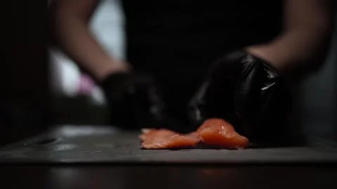 Close-Up of Hands Slicing Fresh Salmon Fillet on a Dark Background Stock Footage 303915895