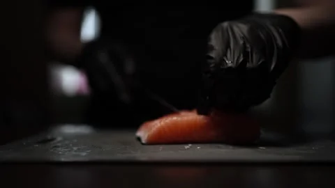 Close-Up of Hands Slicing Fresh Salmon Fillet on a Dark Background Stock Footage 303916201
