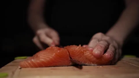 Close-Up of Hands Slicing Fresh Salmon Fillet on a Dark Background Video stock 303920529