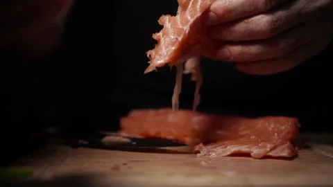 Close-Up of Hands Slicing Fresh Salmon Fillet on a Dark Background Stock Footage 303920864