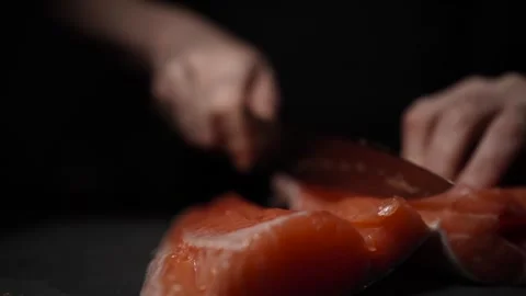 Close-Up of Hands Slicing Fresh Salmon Fillet on a Dark Background 스톡 동영상 303920883