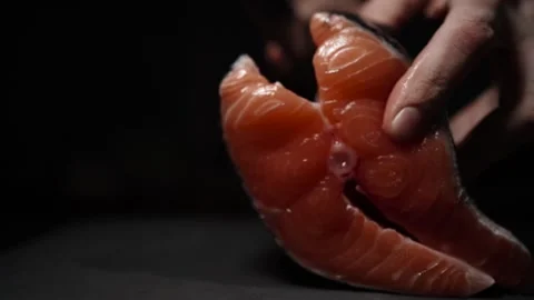 Close-Up of Hands Slicing Fresh Salmon Fillet on a Dark Background Stock-Footage 303920904