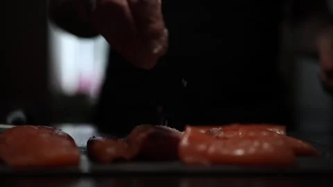 Close-Up of Hands Slicing Fresh Salmon Fillet on a Dark Background Stockbeeldmateriaal 303920922