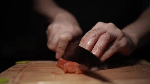 Close-Up of Hands Slicing Fresh Salmon Fillet on a Dark Background Stockbeeldmateriaal 303921407
