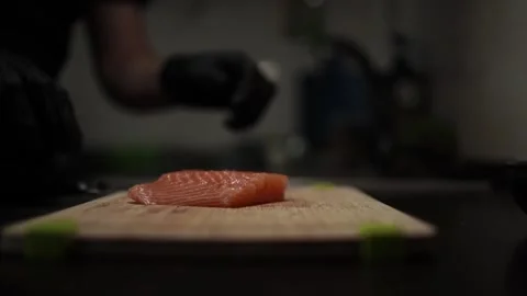 Close-Up of Hands Slicing Fresh Salmon Fillet on a Dark Background 스톡 동영상 303921773