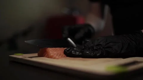 Close-Up of Hands Slicing Fresh Salmon Fillet on a Dark Background Stock Footage 303921780