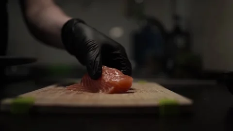 Close-Up of Hands Slicing Fresh Salmon Fillet on a Dark Background Video stock 303921783