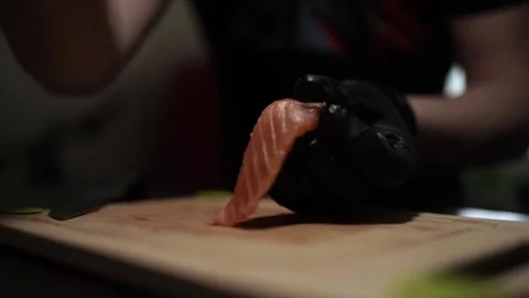 Close-Up of Hands Slicing Fresh Salmon Fillet on a Dark Background 스톡 동영상 303921795