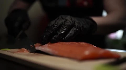 Close-Up of Hands Slicing Fresh Salmon Fillet on a Dark Background Stock Footage 303921799