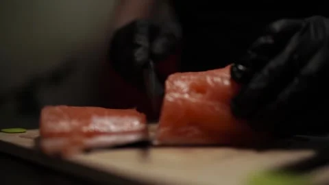 Close-Up of Hands Slicing Fresh Salmon Fillet on a Dark Background 스톡 동영상 303921800