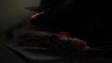 Close-Up of Hands Slicing Fresh Salmon Fillet on a Dark Background Stock Footage 303921838