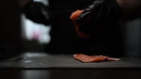 Close-Up of Hands Slicing Fresh Salmon Fillet on a Dark Background Stock Footage 303921877