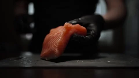 Close-Up of Hands Slicing Fresh Salmon Fillet on a Dark Background 스톡 동영상 303921889
