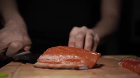 Close-Up of Hands Slicing Fresh Salmon Fillet on a Dark Background Vídeo Stock 303923631