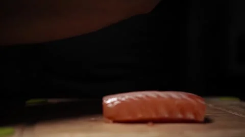 Close-Up of Hands Slicing Fresh Salmon Fillet on a Dark Background 스톡 동영상 303923632