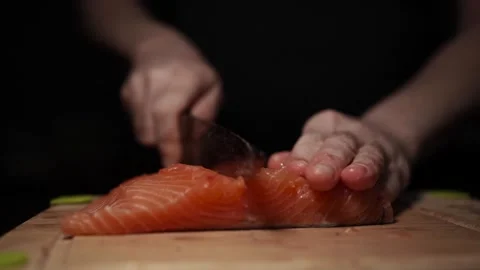 Close-Up of Hands Slicing Fresh Salmon Fillet on a Dark Background Stock Footage 303923657