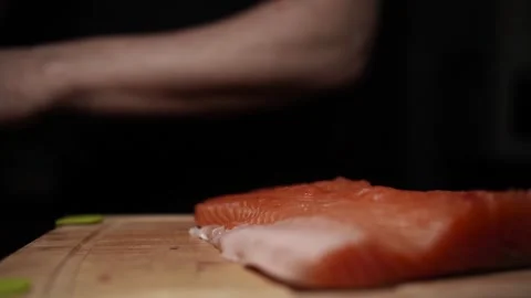 Close-Up of Hands Slicing Fresh Salmon Fillet on a Dark Background Stock-Footage 303923692