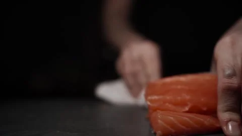 Close-Up of Hands Slicing Fresh Salmon Fillet on a Dark Background 스톡 동영상 303923758