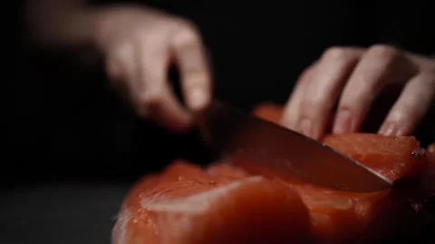 Close-Up of Hands Slicing Fresh Salmon Fillet on a Dark Background Stock Footage 303923767