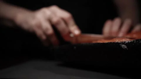 Close-Up of Hands Slicing Fresh Salmon Fillet on a Dark Background Stock-Footage 303923784