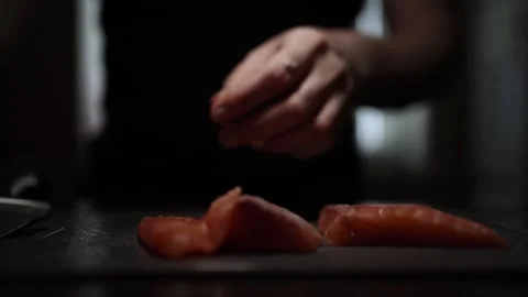 Close-Up of Hands Slicing Fresh Salmon Fillet on a Dark Background Stock Footage 303924093