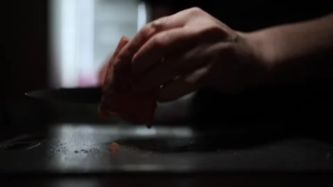 Close-Up of Hands Slicing Fresh Salmon Fillet on a Dark Background Видео 303924189