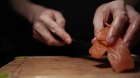 Close-Up of Hands Slicing Fresh Salmon Fillet on a Dark Background 스톡 동영상 303924780