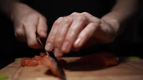 Close-Up of Hands Slicing Fresh Salmon Fillet on a Dark Background 스톡 동영상 303924846