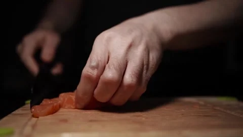 Close-Up of Hands Slicing Fresh Salmon Fillet on a Dark Background 스톡 동영상 303924849