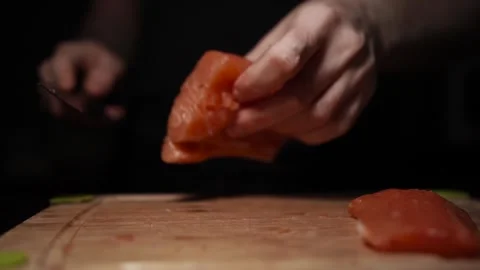 Close-Up of Hands Slicing Fresh Salmon Fillet on a Dark Background Stock-Footage 303924850