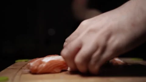 Close-Up of Hands Slicing Fresh Salmon Fillet on a Dark Background Video stock 303925161