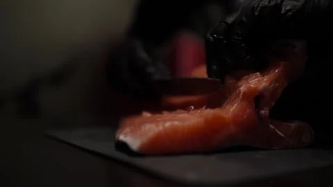 Close-Up of Hands Slicing Fresh Salmon Fillet on a Dark Background Stock-Footage 303925434