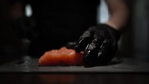 Close-Up of Hands Slicing Fresh Salmon Fillet on a Dark Background Stock Footage 303925464